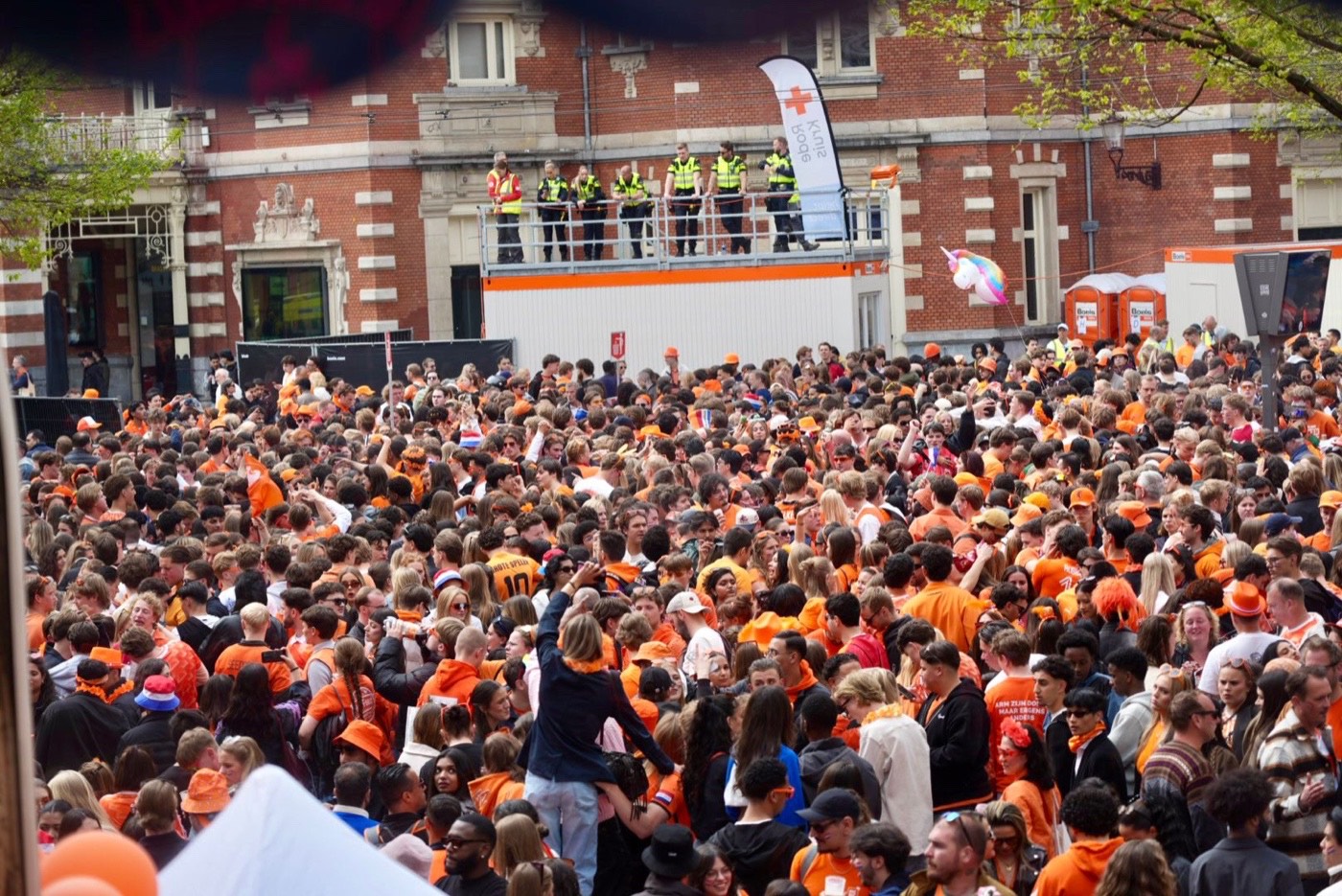 Duizenden bezoekers in het oranje op het Leidseplein, met toezicht vanaf een uitkijkpost