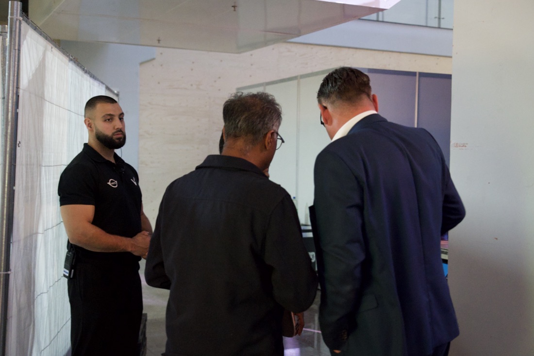 HKS-beveiliger in poloshirt houdt toezicht in een evenementenhal