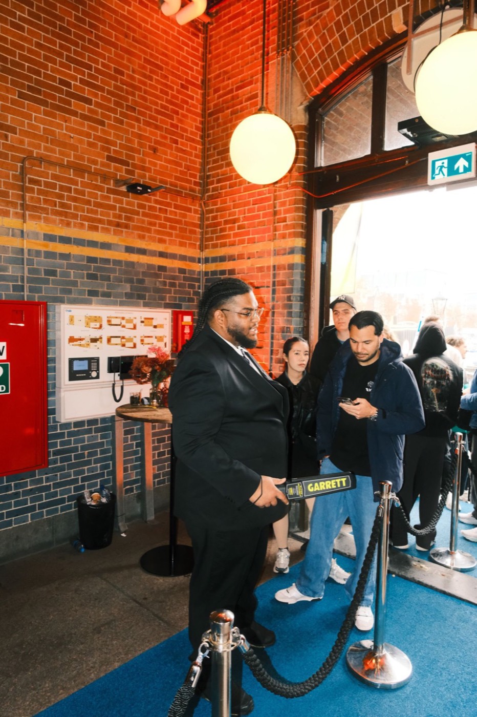 HKS-beveiliger controleert bezoekers met een detector bij de ingang van het Spotify Huis